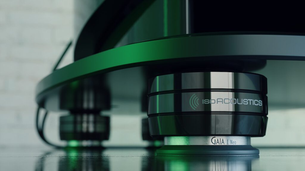 Close-up view of an IsoAcoustics GAIA I Neo isolation foot supporting a high-end audio speaker or equipment, highlighting its polished metal finish and vibration-dampening design on a glossy floor surface.