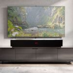 LIVEBOX soundbar beneath a television on a lowboard, with a landscape image above on a gray wall in the living room
