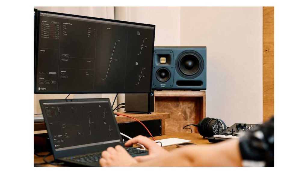 Laptop and screen showing HEDD CTRL software interface next to a blue HEDD studio monitor speaker.