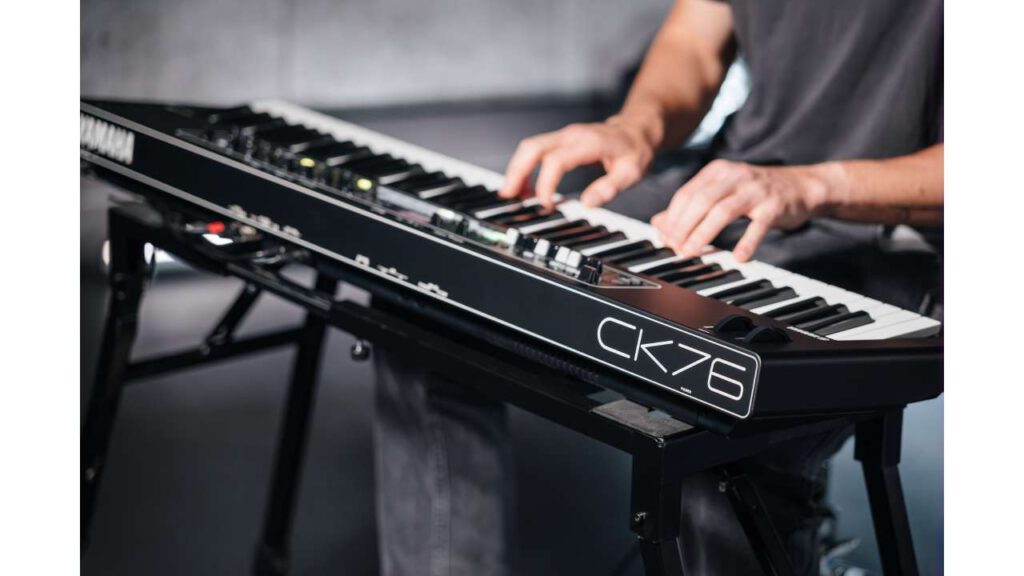 Hands of a musician playing the black Yamaha CK76 stage keyboard.